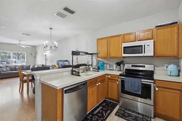 kitchen featuring visible vents, open floor plan, stainless steel appliances, a peninsula, and light countertops