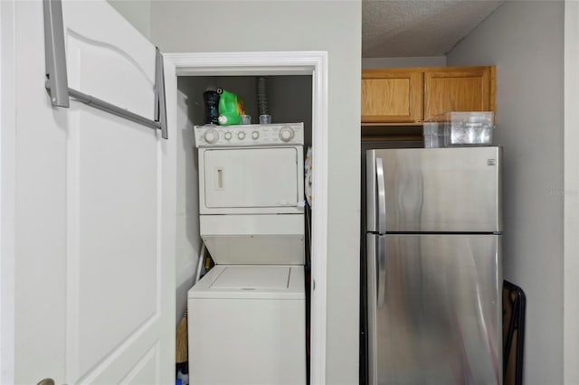 clothes washing area featuring stacked washer and dryer, laundry area, and a textured ceiling