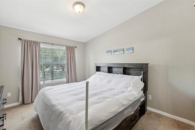 bedroom featuring lofted ceiling, baseboards, and light carpet