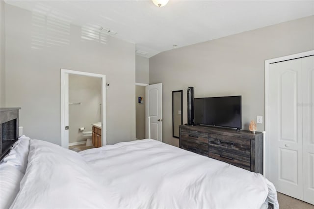 bedroom with a closet, visible vents, ensuite bathroom, and lofted ceiling