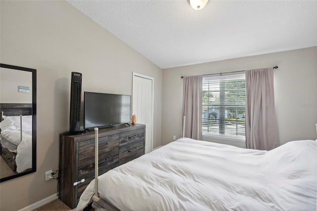 bedroom with vaulted ceiling, baseboards, and carpet floors