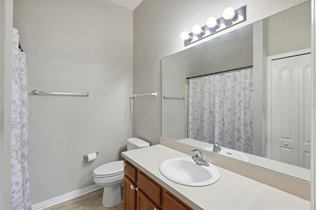 bathroom featuring baseboards, toilet, wood finished floors, and vanity