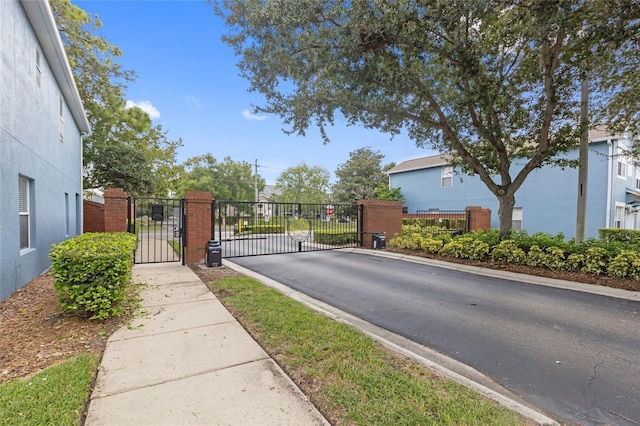 view of street featuring a gate, curbs, sidewalks, and a gated entry