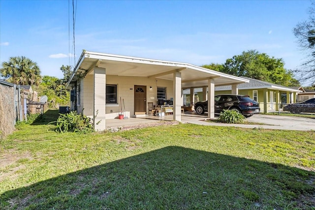 back of property with concrete block siding, fence, a yard, a carport, and central air condition unit