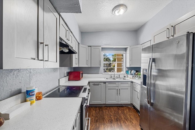 kitchen featuring under cabinet range hood, appliances with stainless steel finishes, light countertops, and a sink