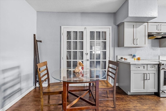 dining room featuring dark wood finished floors, french doors, baseboards, and a textured wall