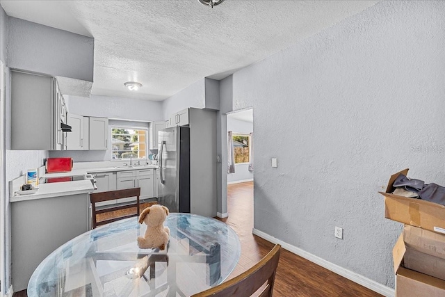 dining area featuring dark wood-type flooring, a textured wall, baseboards, and a textured ceiling