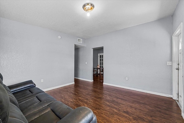 living area featuring visible vents, a textured ceiling, baseboards, and wood finished floors