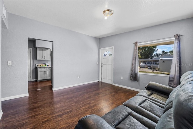 living room featuring a textured wall, baseboards, and wood finished floors