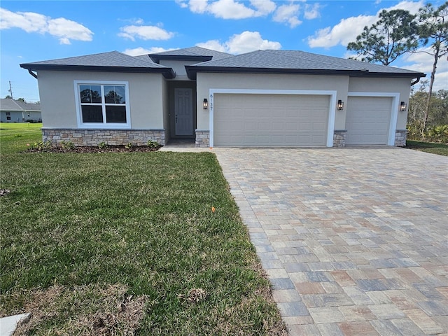 prairie-style house featuring decorative driveway, a garage, stone siding, and stucco siding