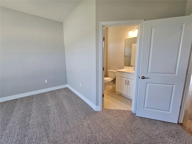 unfurnished bedroom with ensuite bath, light colored carpet, and baseboards