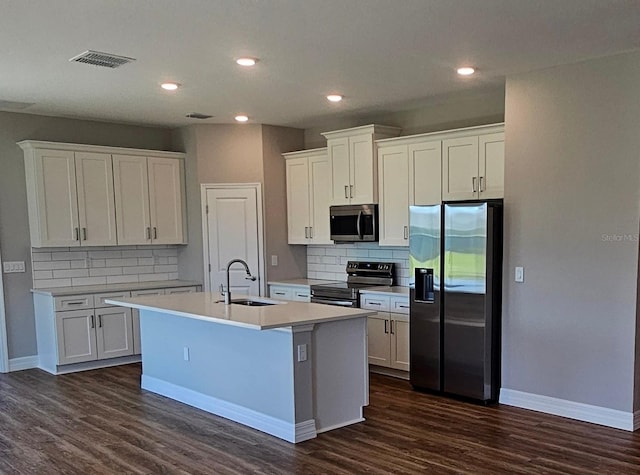 kitchen with visible vents, a kitchen island with sink, a sink, appliances with stainless steel finishes, and white cabinets