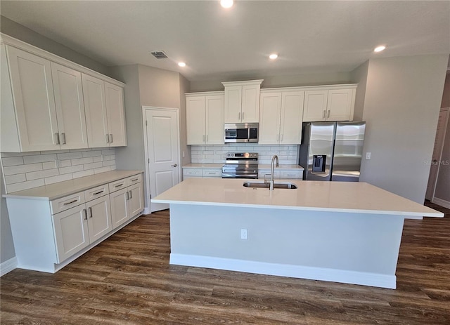 kitchen featuring visible vents, a kitchen island with sink, a sink, dark wood finished floors, and stainless steel appliances