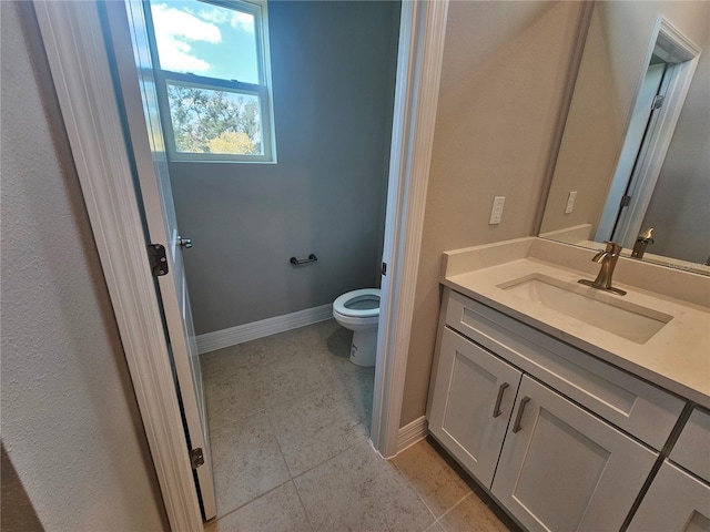 bathroom with tile patterned flooring, toilet, vanity, and baseboards