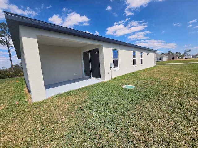 back of property with stucco siding and a lawn