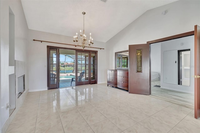 unfurnished dining area with a notable chandelier, french doors, light tile patterned floors, and high vaulted ceiling