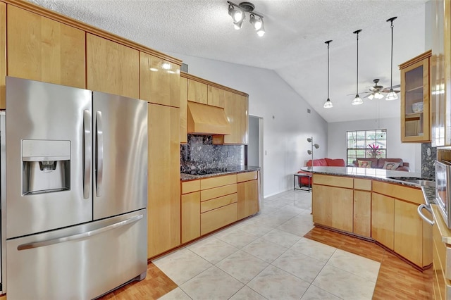 kitchen featuring ventilation hood, a peninsula, lofted ceiling, stainless steel fridge with ice dispenser, and black electric stovetop