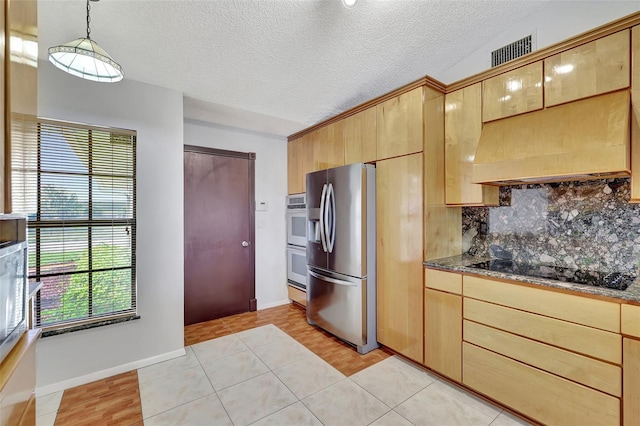 kitchen with premium range hood, visible vents, backsplash, appliances with stainless steel finishes, and light tile patterned floors