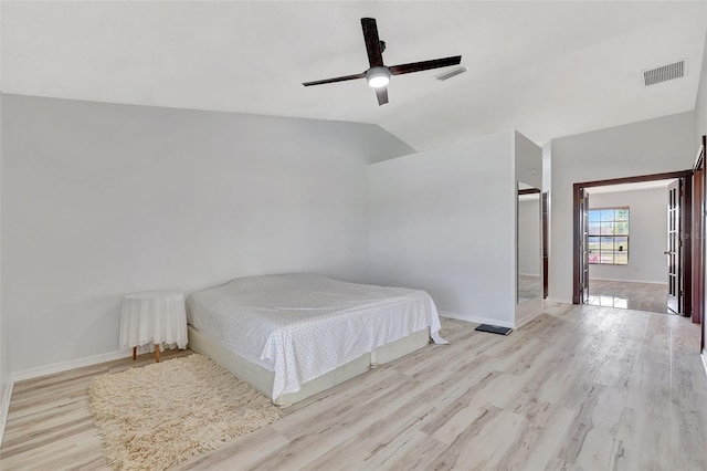 bedroom with visible vents, baseboards, wood finished floors, and vaulted ceiling