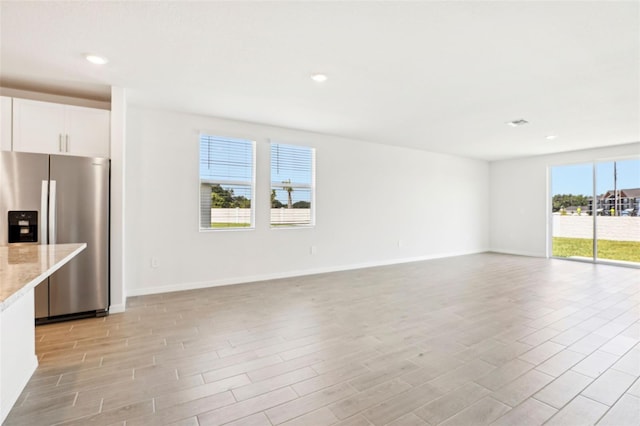 unfurnished living room featuring light wood finished floors, baseboards, and recessed lighting