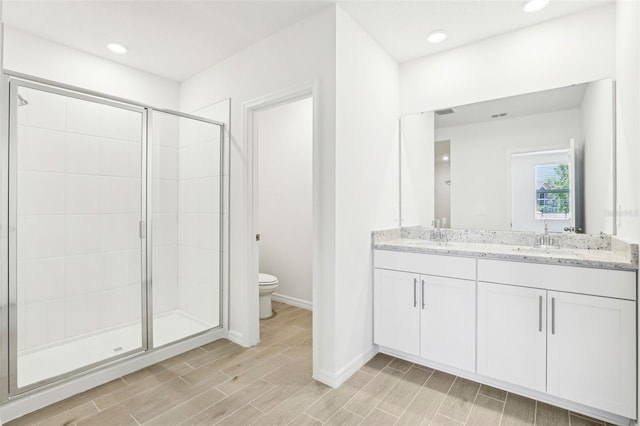 full bath featuring a shower stall, a sink, wood tiled floor, baseboards, and toilet