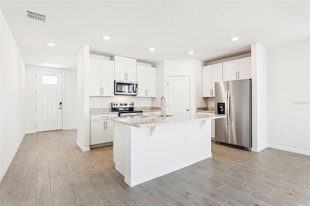 kitchen featuring a kitchen bar, light wood-style flooring, appliances with stainless steel finishes, and baseboards