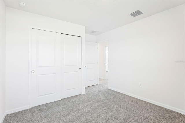 unfurnished bedroom with a closet, carpet, visible vents, and baseboards