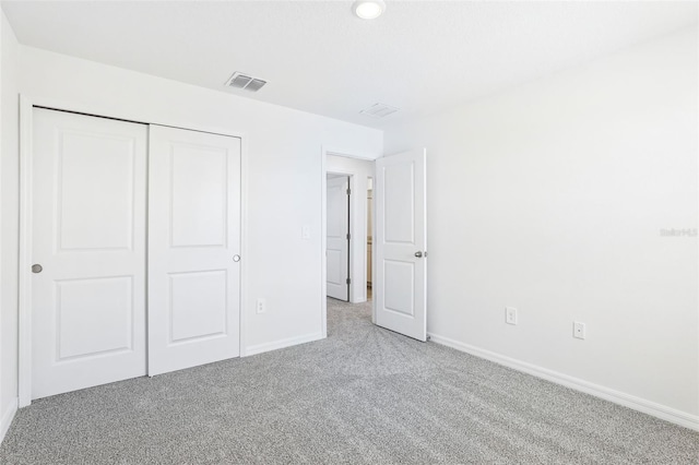 unfurnished bedroom featuring baseboards, a closet, visible vents, and carpet