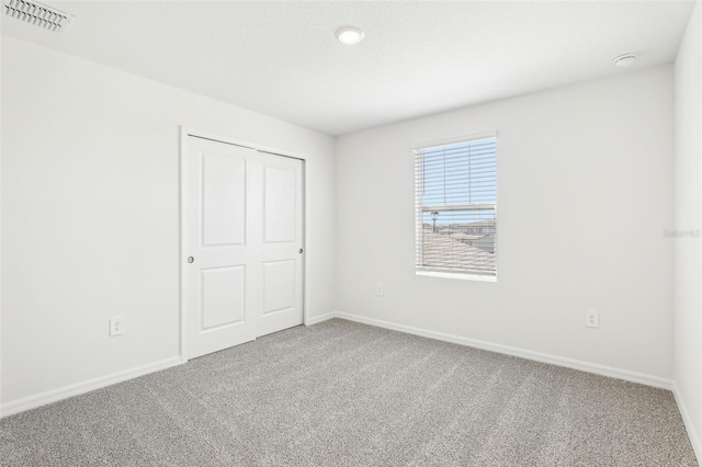 unfurnished bedroom featuring baseboards, carpet flooring, and visible vents