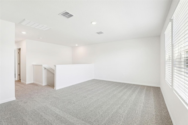spare room featuring light carpet, baseboards, visible vents, and recessed lighting