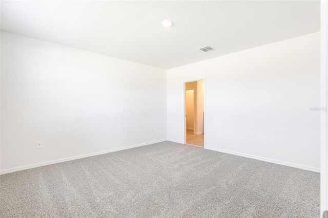 empty room with visible vents, baseboards, and light colored carpet