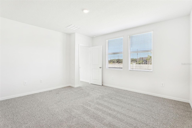 carpeted empty room featuring visible vents and baseboards