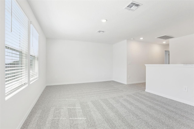 carpeted empty room featuring baseboards, visible vents, and recessed lighting