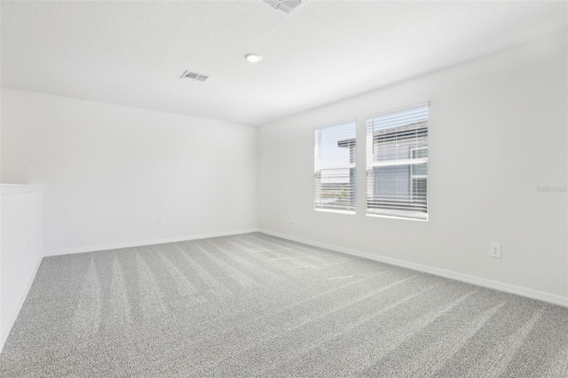 empty room featuring baseboards, visible vents, and carpet