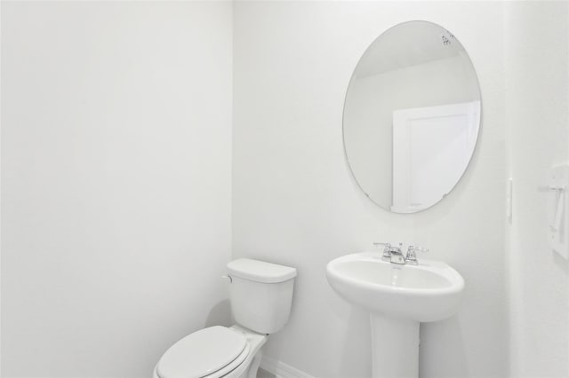 bathroom with toilet, a sink, and baseboards