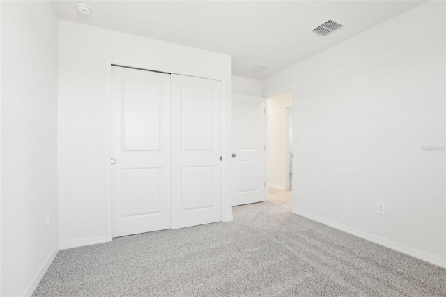 unfurnished bedroom featuring light colored carpet, baseboards, visible vents, and a closet