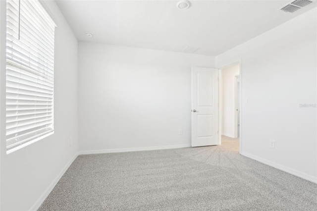 unfurnished room featuring light colored carpet, baseboards, and visible vents