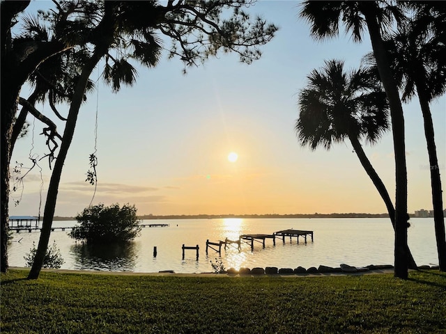 view of dock with a yard and a water view