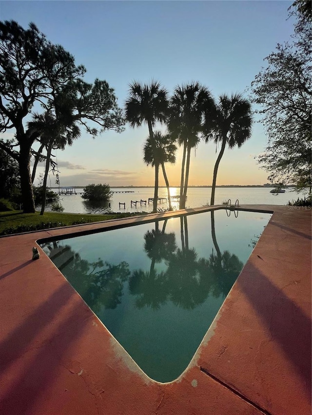 pool at dusk featuring a water view