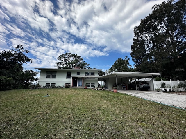 view of front facade featuring a front lawn, fence, entry steps, a carport, and driveway