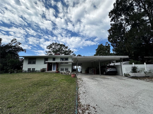 view of front facade featuring an attached carport, a front yard, fence, gravel driveway, and entry steps