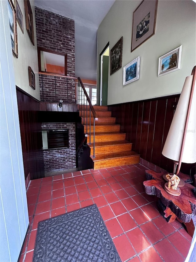 stairs featuring wooden walls, wainscoting, and a tile fireplace