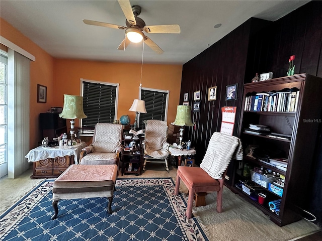 living area featuring carpet flooring and a ceiling fan