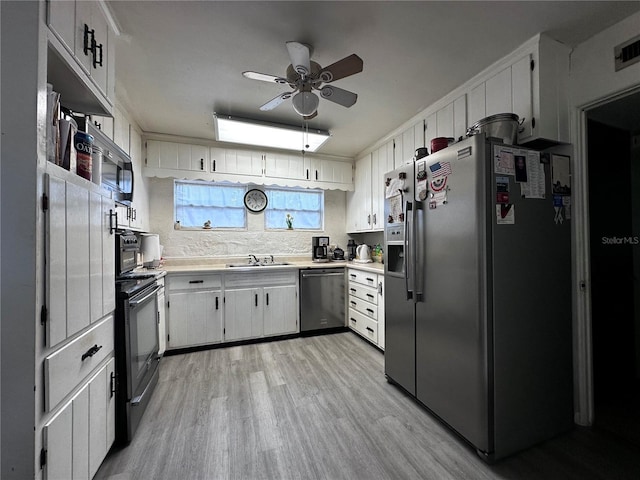 kitchen with a ceiling fan, a sink, stainless steel appliances, light countertops, and light wood-type flooring