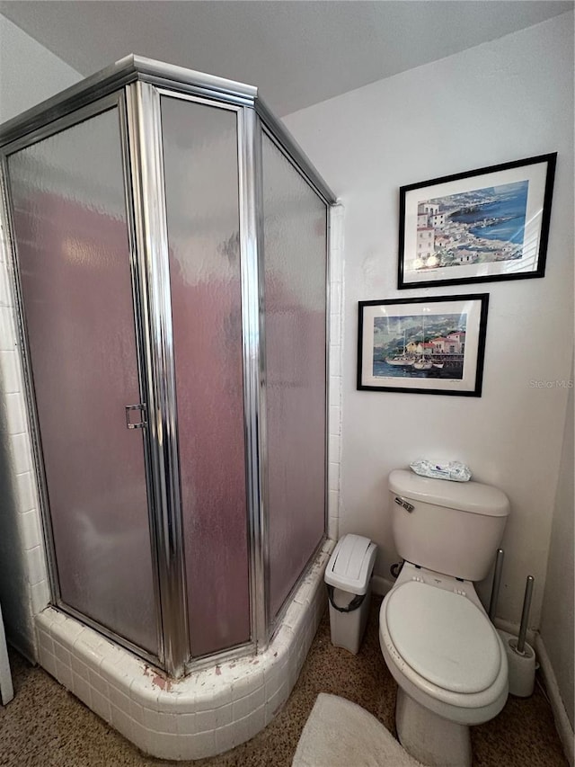 bathroom featuring baseboards, toilet, and a stall shower