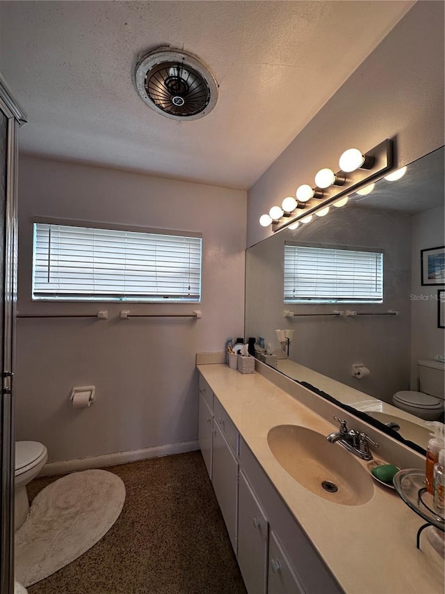 bathroom featuring vanity, toilet, baseboards, and a textured ceiling