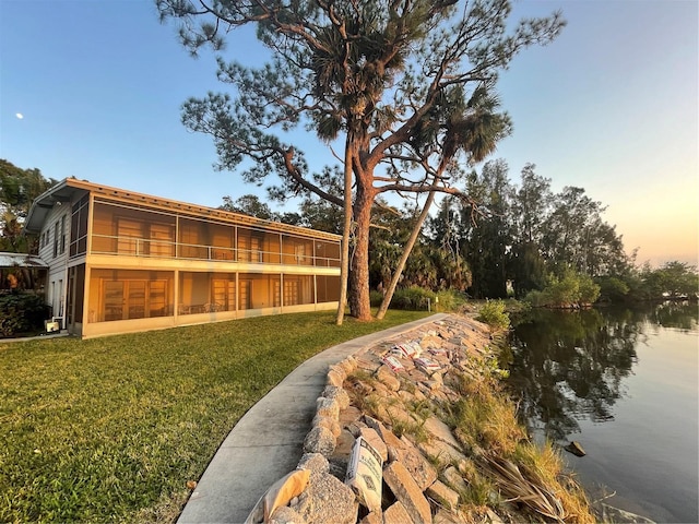 yard at dusk featuring a water view