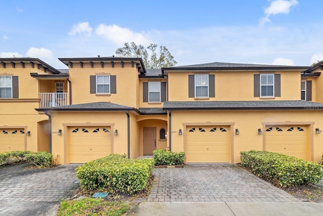 townhome / multi-family property with decorative driveway, an attached garage, and stucco siding