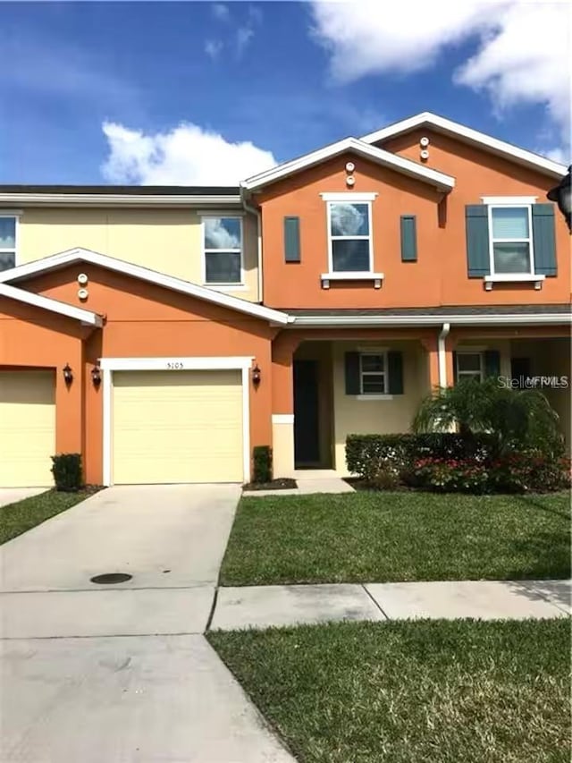 view of front of property featuring stucco siding, concrete driveway, and a front lawn