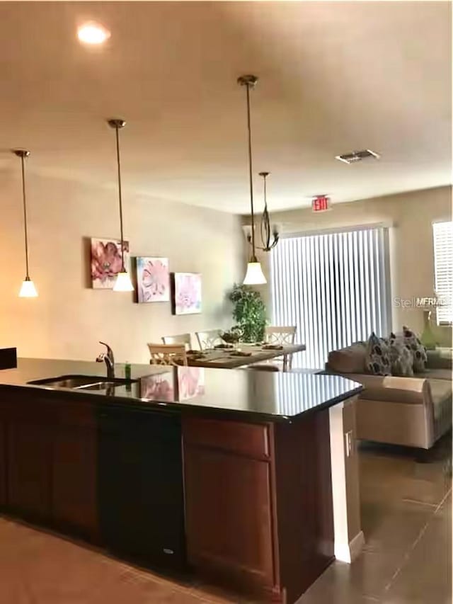 kitchen with decorative light fixtures, visible vents, dark countertops, and a sink